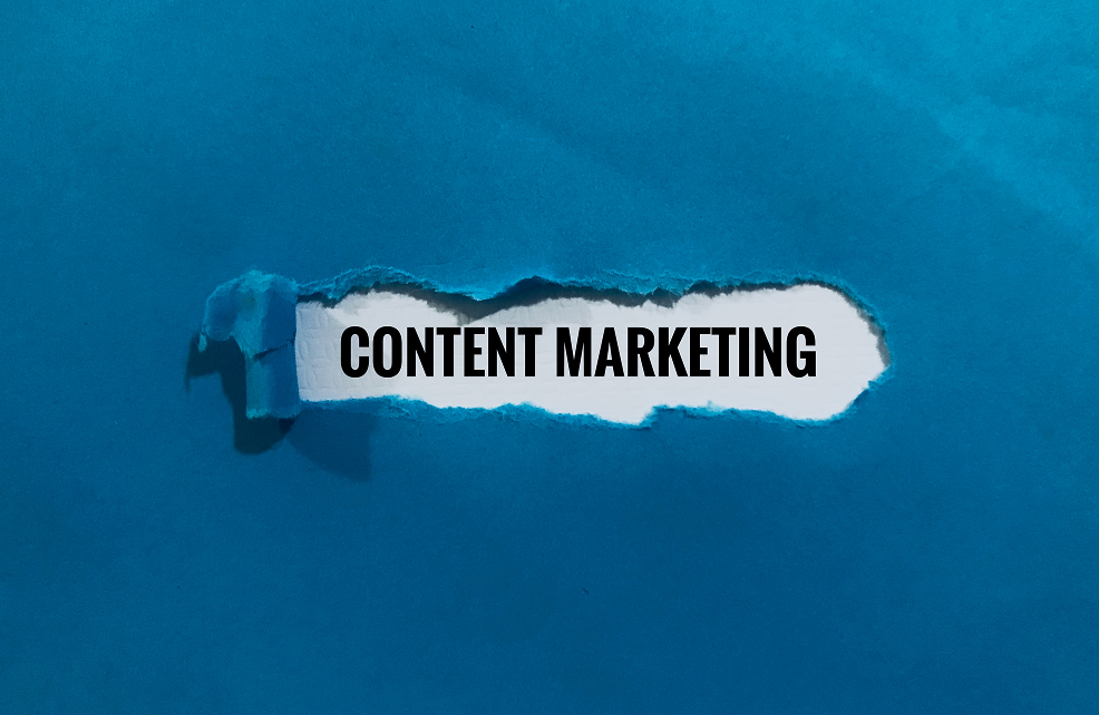 A torn blue paper revealing the words CONTENT MARKETING inside.